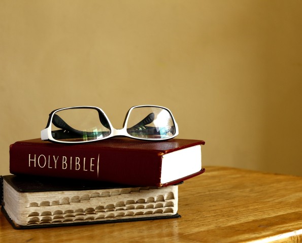 Photo of a Holy Bibles on a table and eyeglasses